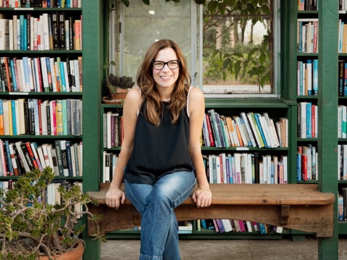 Author Amy Thielen in front of a stack of books.