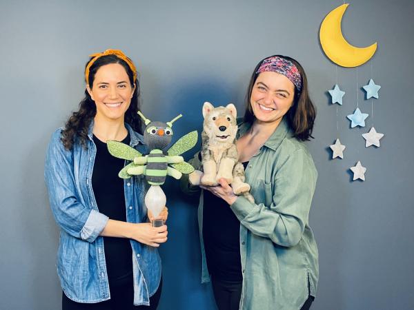 Two women from Firefly Family Theatre holding a firefly and a wolf stuffie.