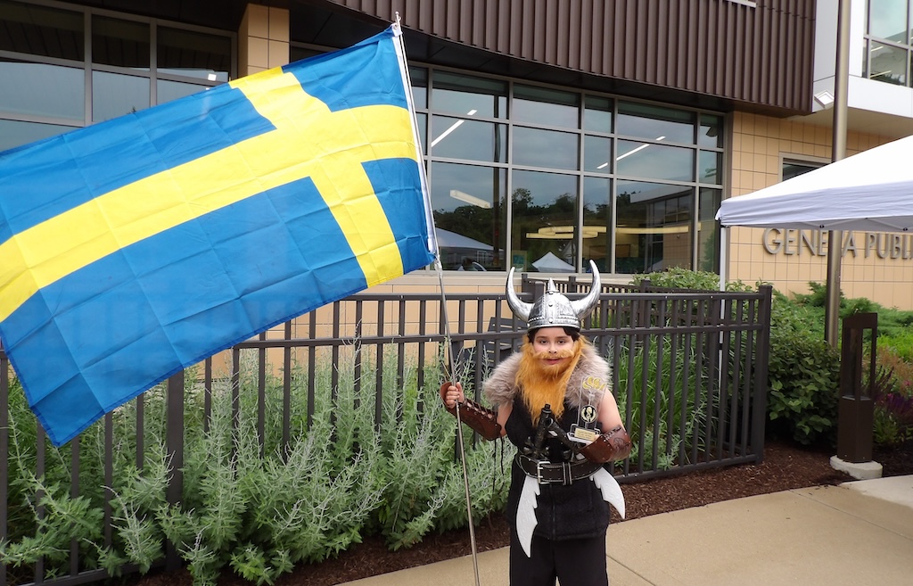 A boy in viking attire holding the Swedish flag.