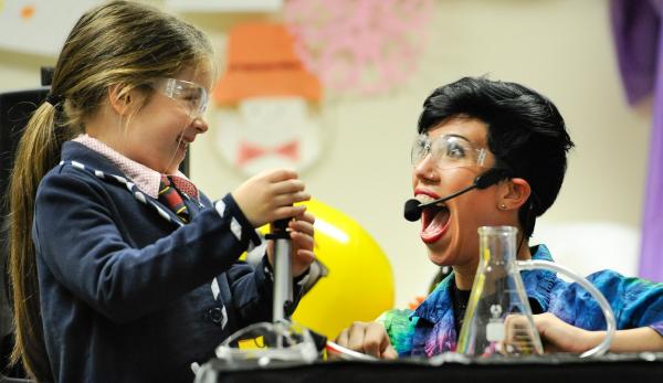 A girl and a woman smiling while doing an experiment.