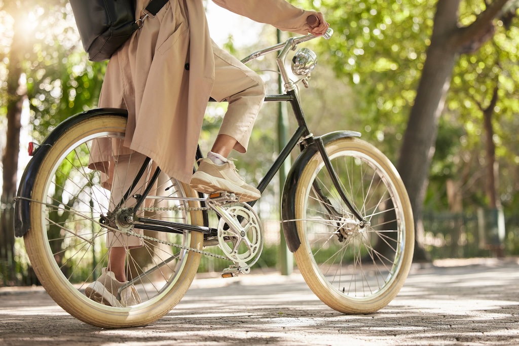 Closeup and feet of a casual cyclist traveling on a bike in a park.