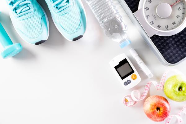 A pair of running shoes, water, glucose monitor, scale, tape measurer, and two apples.