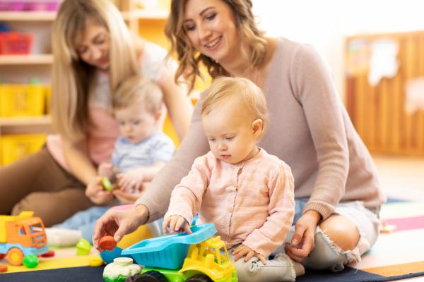 Two mothers and babies playing with toys.