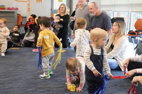 Babies and toddlers playing with colorful strings.
