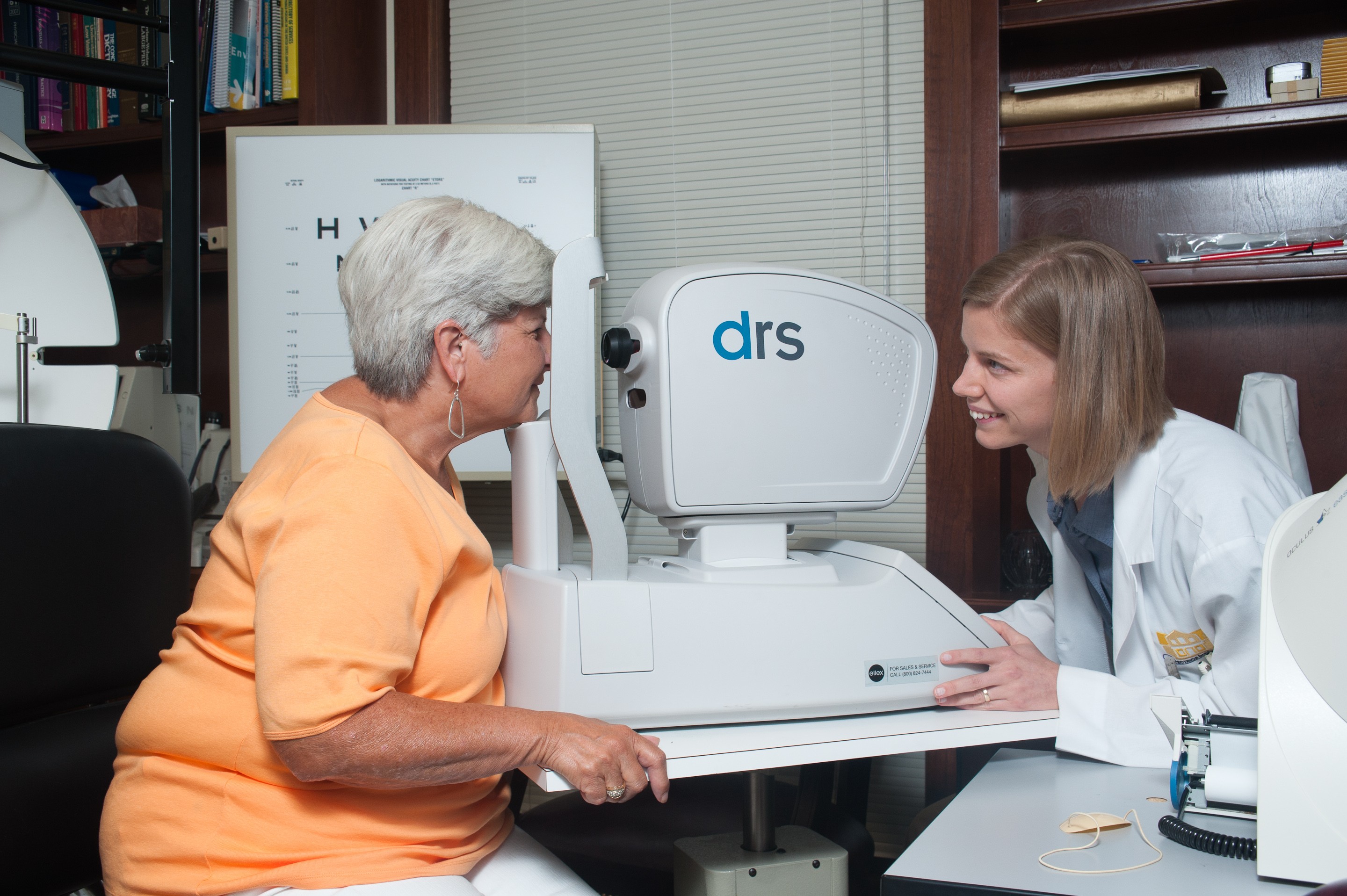 A doctor examining an older woman's vision using specialized equipment.