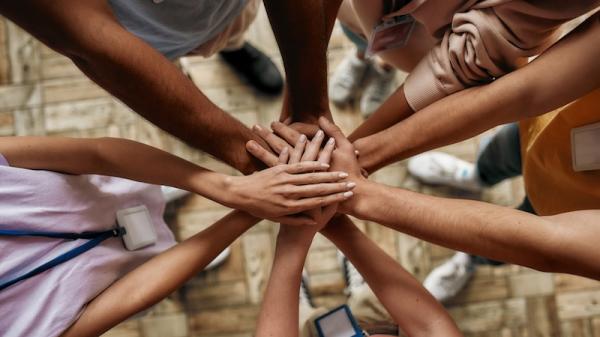 Top view of diverse young volunteers putting their hands on top of each other