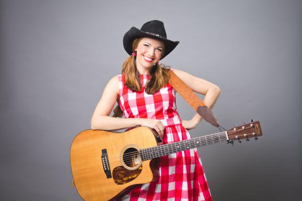 Miss Jamie smiling with her guitar.