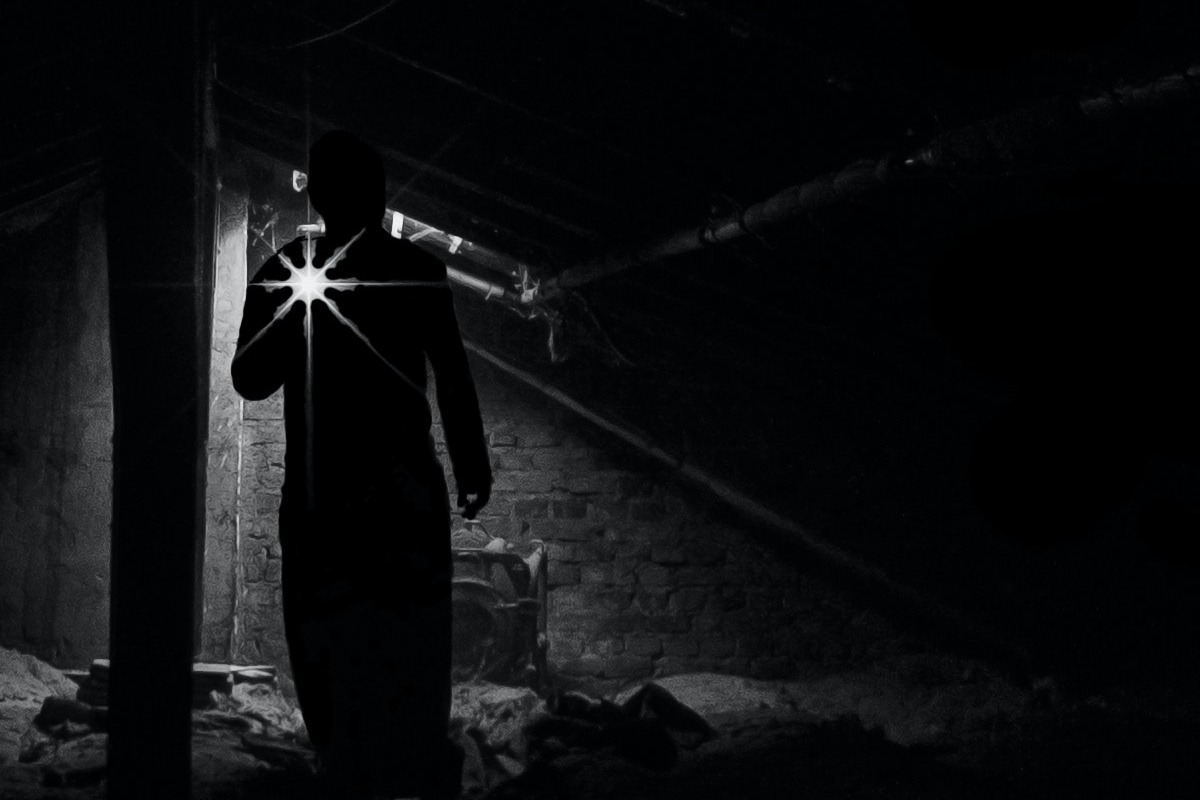 A man holding a flashnight in the darkness.
