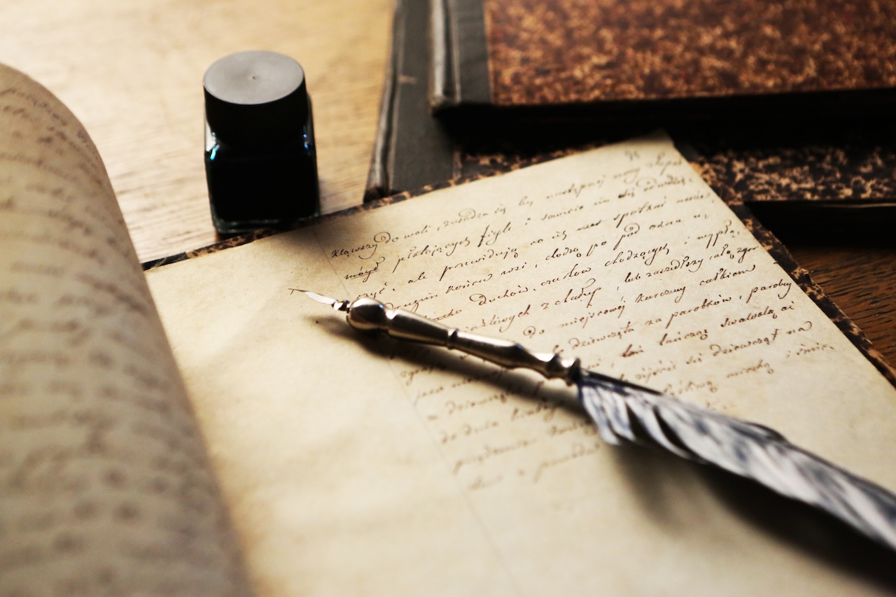 An ink pen on top of a notebook with cursive writing.