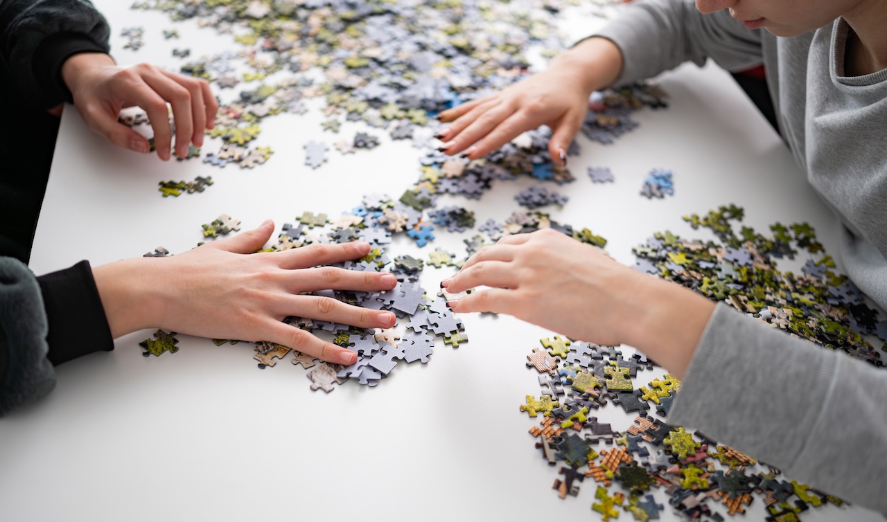 Hands assembling a puzzle.