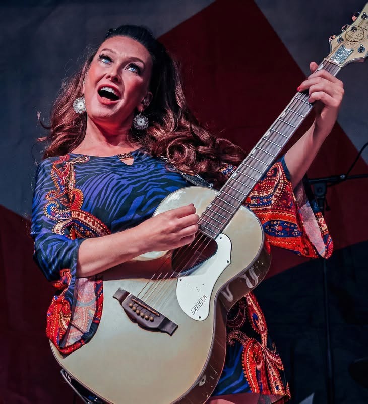 Rosie from Rosie & The Rivets playing the guitar.