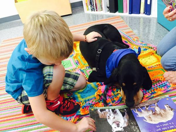 Child reading to a dog.