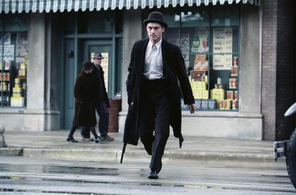 A man in prohibition era clothing walking outside. From the film "Road to Perdition."