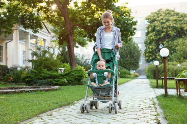 Woman pushing a stroller with a baby through on a residential sidewalk.