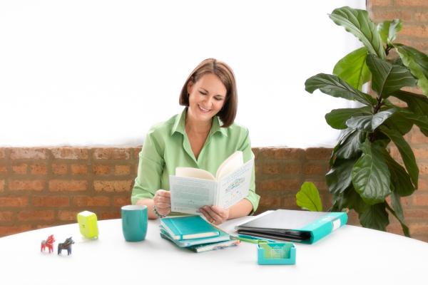 A woman smiling while reading a book.