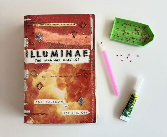 A bedazzled book, gems, and glue.