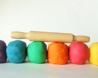 Colorful balls of play-doh and a rolling pin.