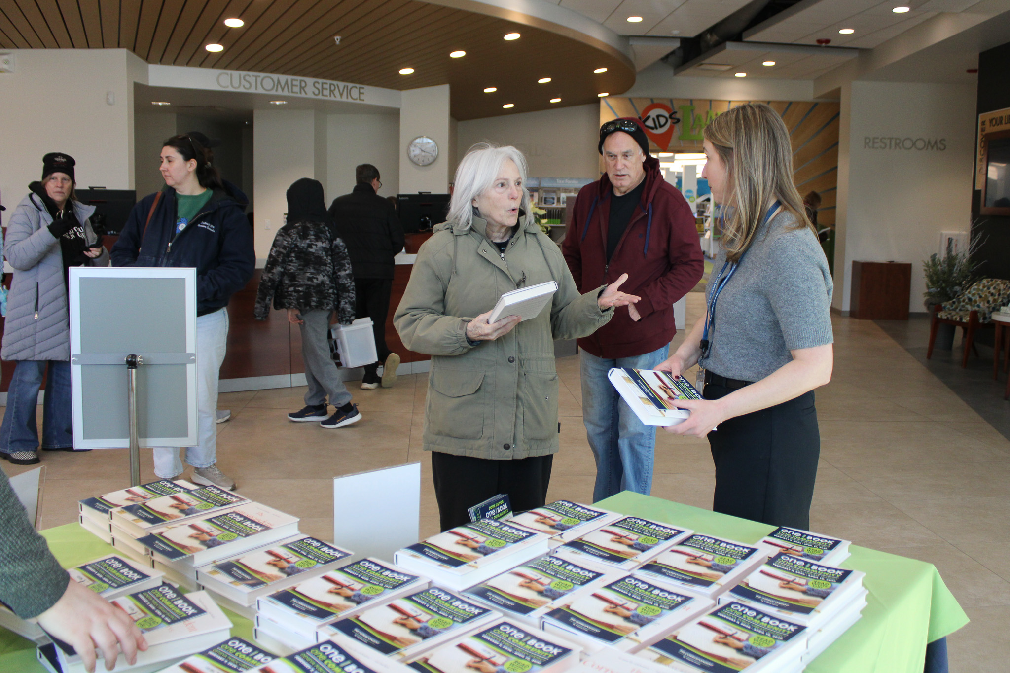 Patron speaking with staff member in front of a table filled with giveaway books.